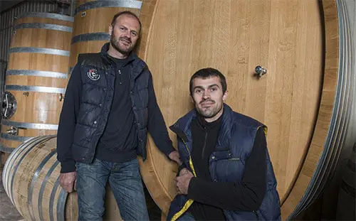 Twee mannen staan voor een wijnvat in Ile d’Olonne. 