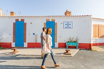 Twee mensen lopen langs een huis in Saint-Gilles-Crouix-de-Vie in Frankrijk.