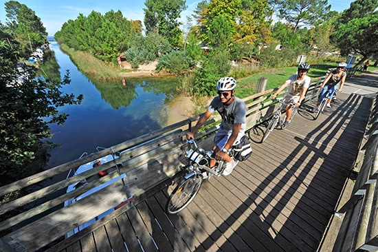 Fietsers steken een kleine houten brug in Les Landes over.