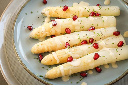 Een bord met asperges uit Landes en granaatappel.