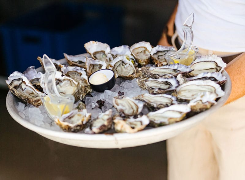 Een man draagt een schaal met oesters.