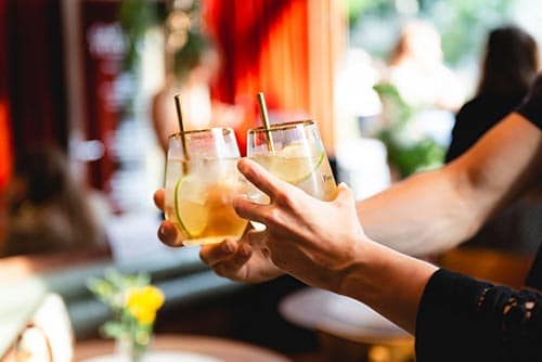 Twee mensen proosten met een cocktail met pineau des Charentes.