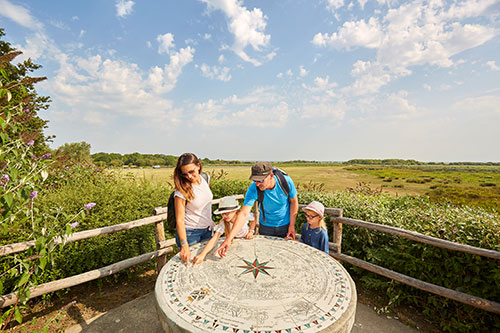 Een gezin staat rond een zonnewijzer in het natuurpark Brière.