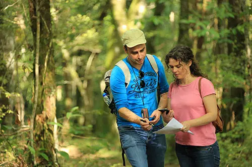 Twee mensen staan in een bos en bekijken een formulier tijdens Geocoaching in Frankrijk.
