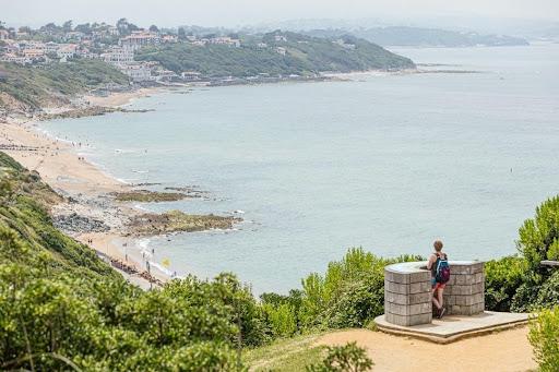 Een wandelaar kijkt uit over de bergen en de zee in Pays Basque.